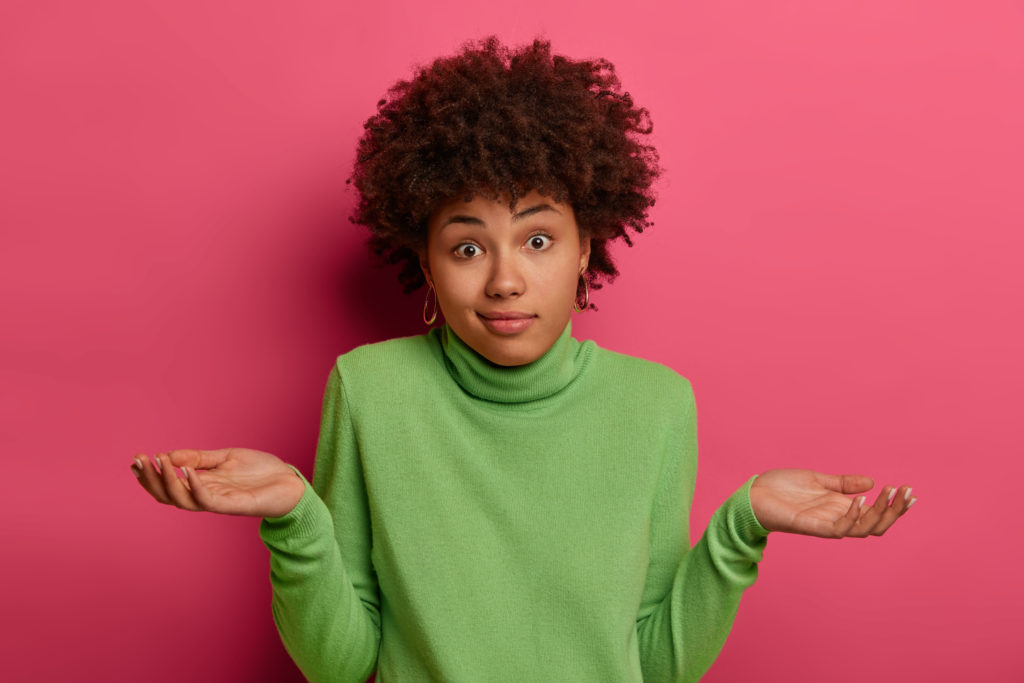 Indifferent Confused Black Woman Spreads Palms Confusingly, Has Doubts, Wears Green Turtleneck, Has Hesitant Face Expression, Isolated Over Pink Background, Has No Idea, Puzzled To Give Answer - OFFICE CONT - Contabilidade Digital para você e sua empresa